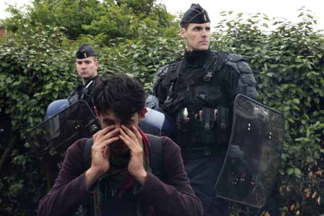 French riot police evict an Afghan man in a crackdown on Calais camps housing migrants aiming to reach the UK. Picture: Reuters