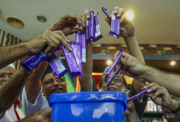 Members of the Malaysian Muslim Wholesalers and Retailers Association throw Cadbury chocolate into a dustbin. Picture: Reuters
