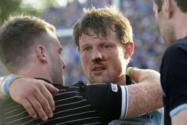 Bloodied in battle: Peter Horne is consoled at full-time. Picture: SNS