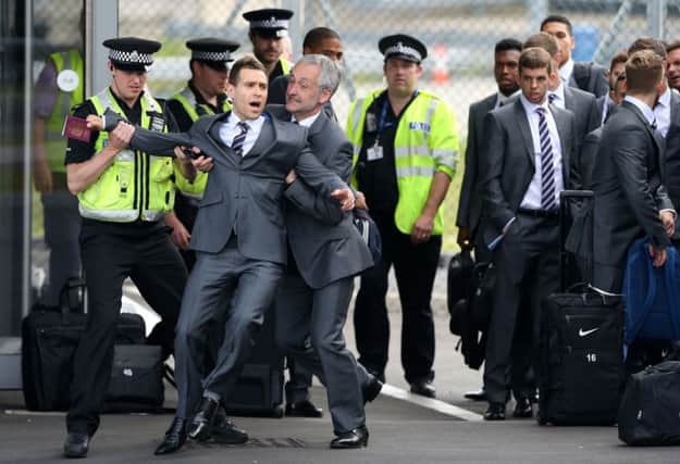 Comedian Simon Brodkin is led away from the England party at Luton Airport after his attempted stunt. Picture: PA