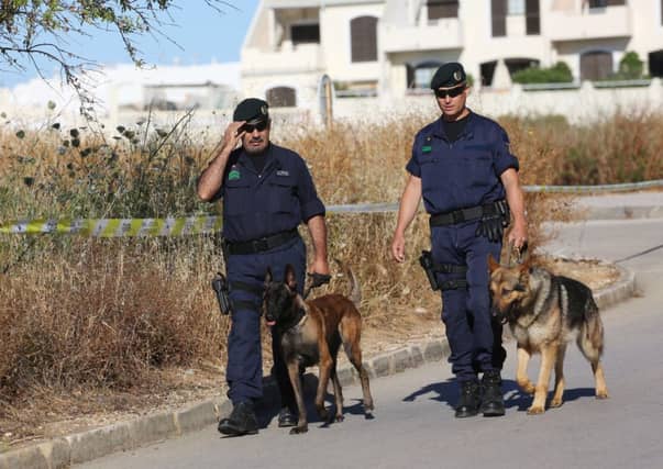 Portuguese police officers walk with dogs near a cordoned off area of scrubland close to where Madeleine McCann went missing seven years ago. Picture: PA