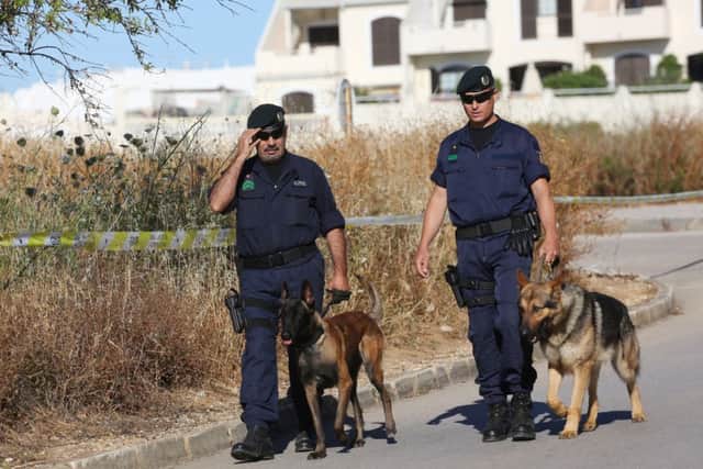 Portuguese police officers walk with dogs near a cordoned off area of scrubland close to where Madeleine McCann went missing seven years ago. Picture: PA