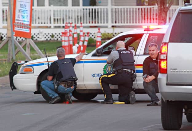Armed police take cover as they investigate a possible sighting of Justin Bourque the man suspected of killing the officers. Picture: AP