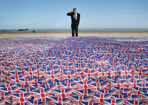 Fred Holborn salutes Union flags carrying thank you messages on Gold beach. Picture: Getty