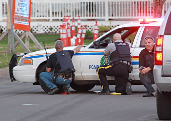 Police officers take cover behind their vehicles in Moncton, New Brunswick. Picture: AP
