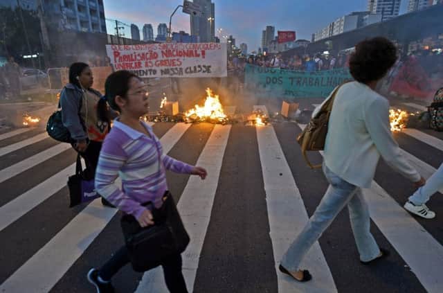 Commuters pass burning rubbish bags in Sao Paulo. Picture: Getty