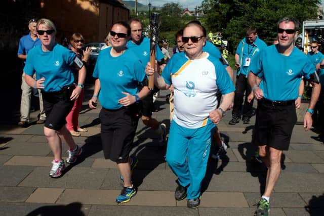 Actor Brian Cox carries the Queen's Baton to through the town of Roslin. Picture: Hemedia
