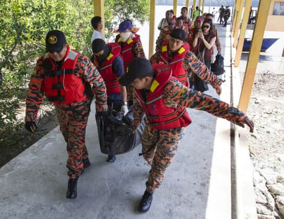 Rescue workers carry a body to shore at Pantai Kelanang, near where a boat sank which was taking workers to Indonesia. Picture: AP
