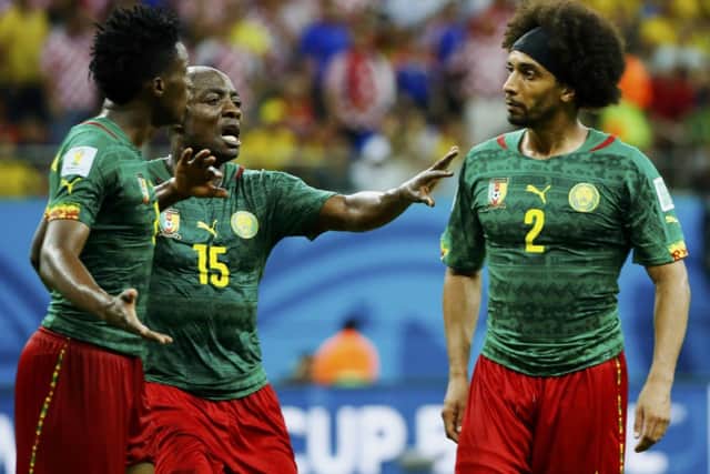 Cameroons Achille Weboc tries to separate Benjamin Moukandjo and Benoit AssouEkotto. Picture: Reuters