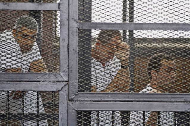 Mohamed Fahmy, left, Peter Greste, centre, and Baher Mohammed sit in the defendants cage of the Cairo court. Picture: AP