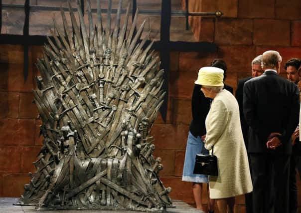 The Queen looks at the Iron Throne as she meets members of the cast on the set of the television series Game of Thrones in Belfast. Picture: Reuters