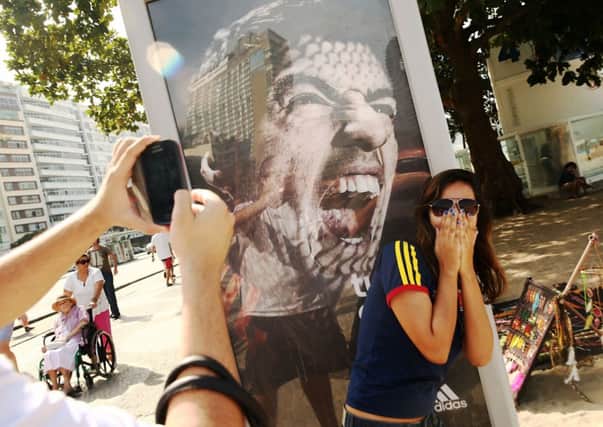A woman takes a photo next to a Suarez ad on Copacabana Beach. Picture: Getty
