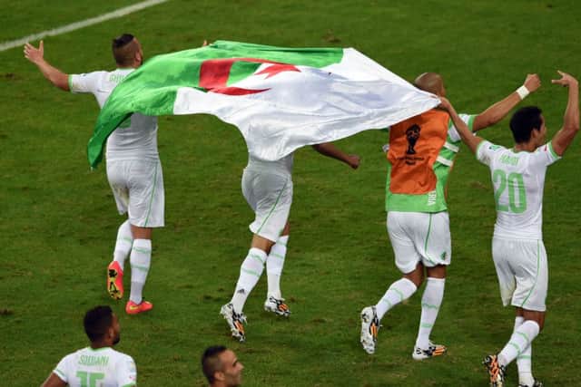 Algeria players run with the national flag as they celebrate their victory. Picture: Getty