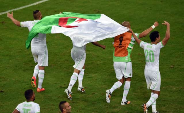 Algeria players run with the national flag as they celebrate their victory. Picture: Getty