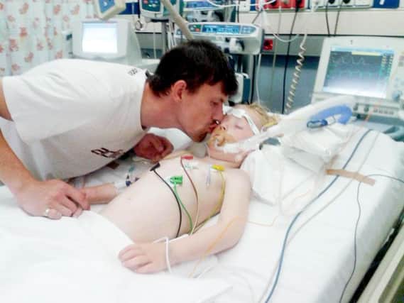 Steven Simpson kisses his daughter Cally Simpson as the four year old lies unconscious in a Spanish hospital. Picture: SWNS