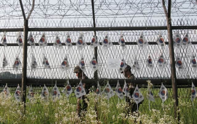 South Korean soldiers patrol through the wire fence hung with national flags in Paju, close to the border with North Korea. Picture: AP