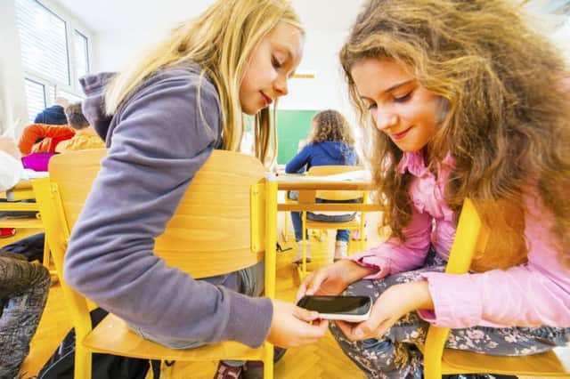 Primary school students cheating in classroom with smartphone
