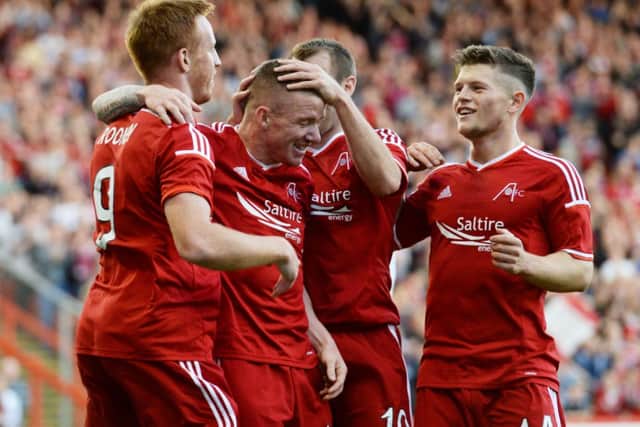 Jonny Hayes is mobbed by his Aberdeen team-mates as they celebrate his goal. Picture: SNS