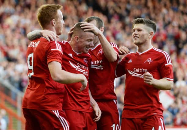 Jonny Hayes is mobbed by his Aberdeen team-mates as they celebrate his goal. Picture: SNS