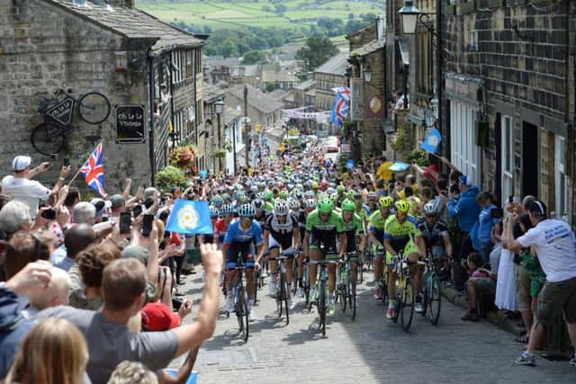 The peloton rides up Main Street as stage two of the Tour de France passes through Haworth. Picture: PA