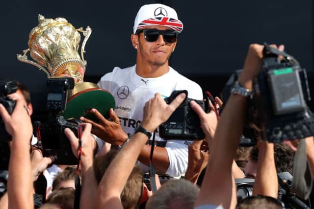 Lewis Hamilton shows off the trophy to photographers at Silverstone yesterday. Picture: PA