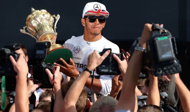 Lewis Hamilton shows off the trophy to photographers at Silverstone yesterday. Picture: PA