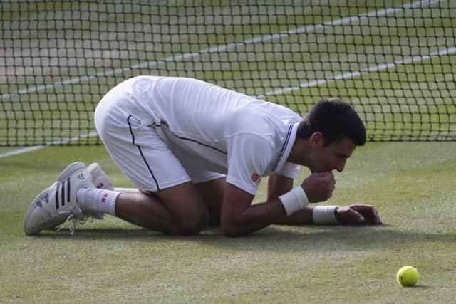 Novak Djokovic eats the grass on centre court as he celebrates defeating Roger Federer. Picture: AP