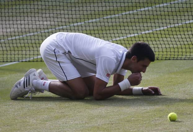 Novak Djokovic eats the grass on centre court as he celebrates defeating Roger Federer. Picture: AP