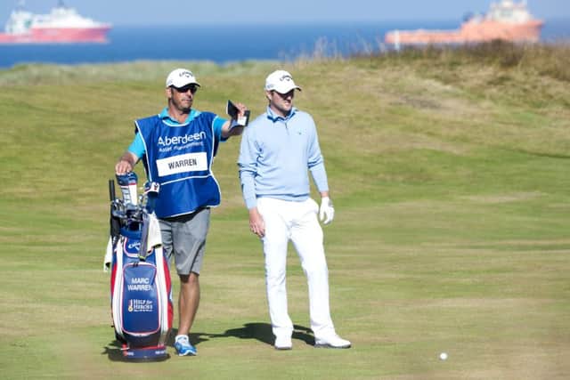 Marc Warren and his caddy discuss the best line playing the 18th hole during day two of the Aberdeen Asset Management Scottish Open. Picture: PA