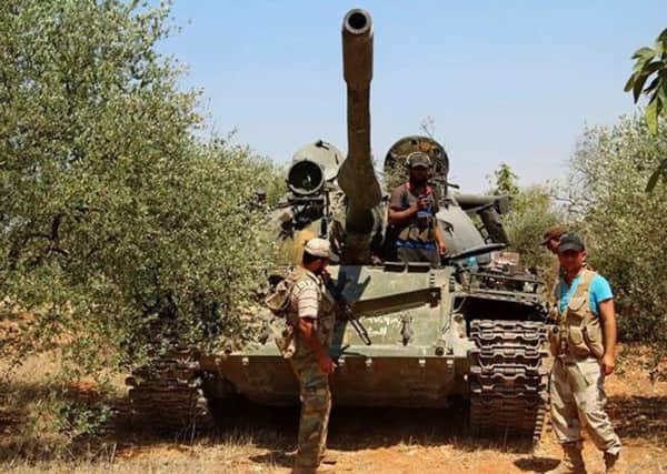 Syrian rebels standing next to a tank that was captured from the Syrian government forces at the al-Dahman checkpoint, in southern Idlib, northern Syria. Picture: AP