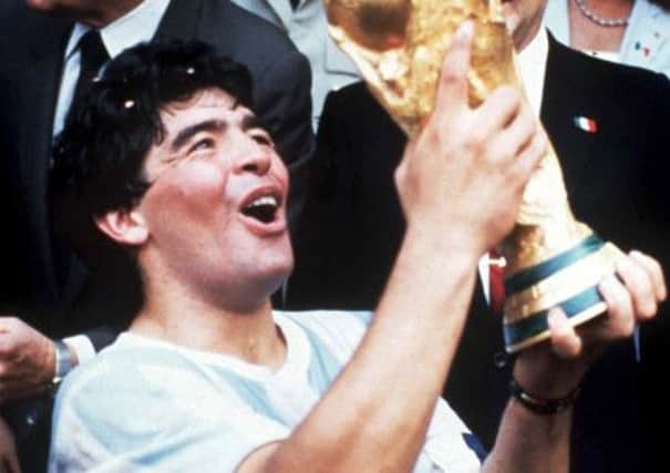 A victorious Diego Maradona admires the World Cup in 1986
