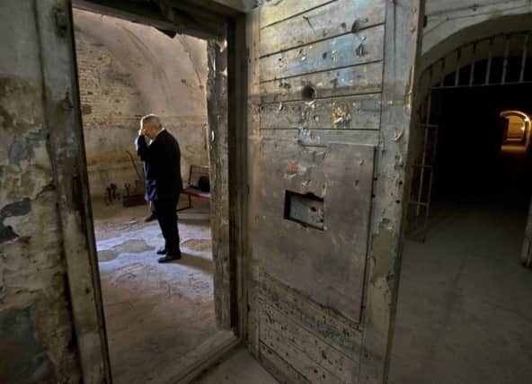 A former political prisoner is overcome as he recalls his time incarcerated in a Romanian prison cell. Picture: AP