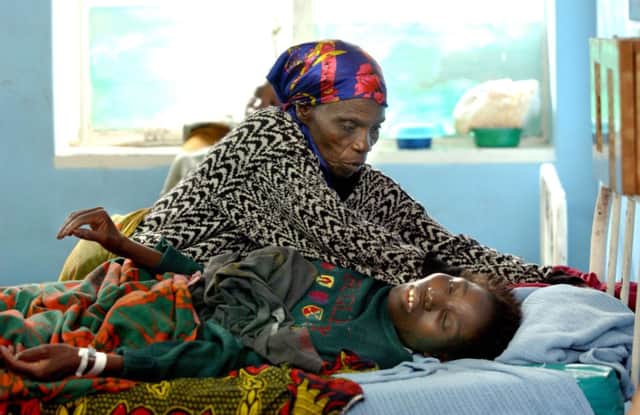 A Malawian woman suffering from the HIV virus is helped by a relative in her bed. Picture: Getty