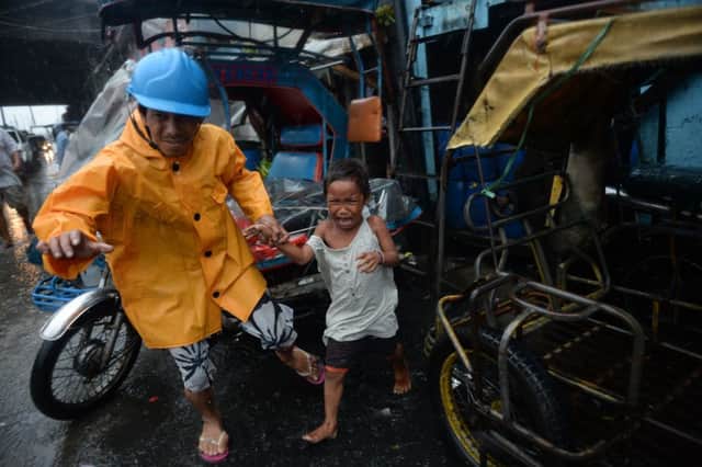 A youngster is led to safety in Manila; memories of last years super typhoon are still raw in the Philippines. Picture: Getty