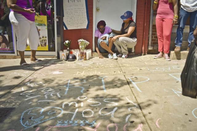Jewel Miller, seated left, is comforted by a friend as she and her three-month-old daughter Legacy sit next to a memorial scene for Legacy's father, Eric Garner. Picture: AP