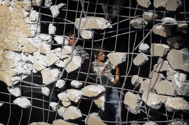 Palestinian children peer through the remnants of a reinforced concrete wall of a mosque yesterday. Picture: Getty
