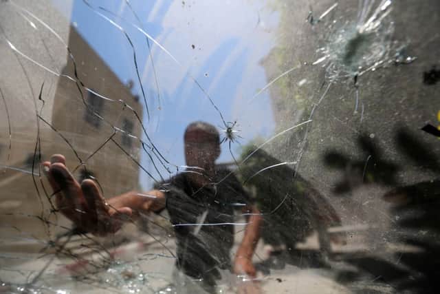 A Palestinian examines a damaged window at Gazas Aqsa Martyrs hospital, damaged in an air strike. Picture: AP