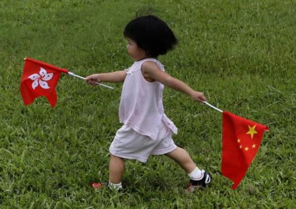 A girl runs with a Chinese national flag and a Hong Kong flag at a military base during an open day event of the Liberation army in Hong Kong. Picture: AP