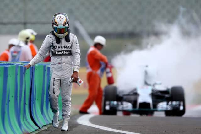Lewis Hamilton walks disconsolately away as a marshal extinguishes the flames from his Mercedes. Picture: Mark Thompson/Getty