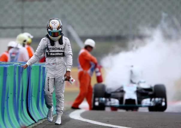 Lewis Hamilton walks disconsolately away as a marshal extinguishes the flames from his Mercedes. Picture: Mark Thompson/Getty