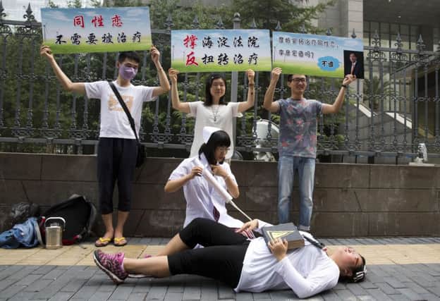 LGBT campaigners pretend to carry out electric shock treatment on one of their number outside the Beijing court. Picture: AP