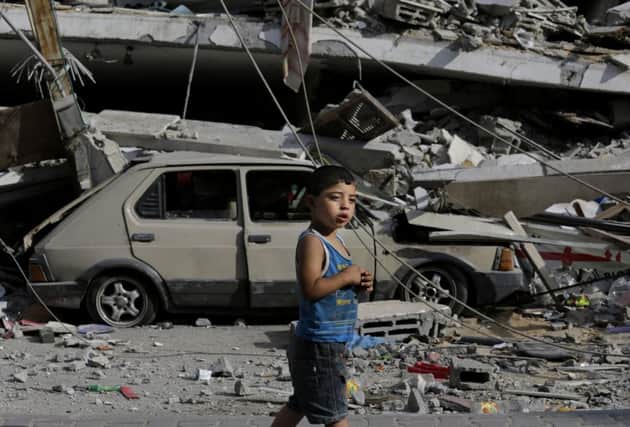 A Palestinian boy walks past a six-story building, destroyed by an Israeli strike. Picture: AP