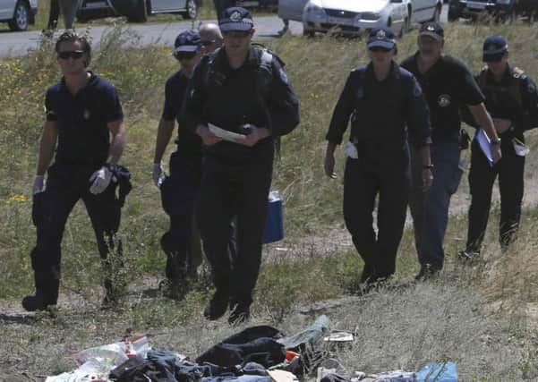 Members of a group of international experts walk past passengers' belongings at the site where Malaysia airlines flight MH17 crashed. Picture: AP