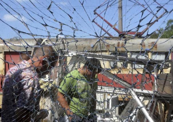 Men are seen through broken glass as they gather after an air strike in Donetsk . Picture: Reuters