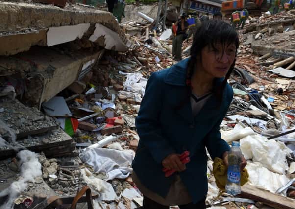 An earthquake survivor, carrying a bottle of water, stumbles through the ruins of buildings destroyed by the tremor in Yunnan. Picture: Getty