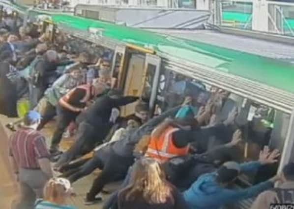 Passengers help free a man trapped between the train and a platform at a Perth train station. Picture: YouTube