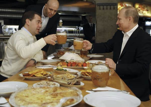Dmitry Medvedev, left, and Vladimir Putin tuck into a meal in a restaurant in Moscow. Picture: Reuters