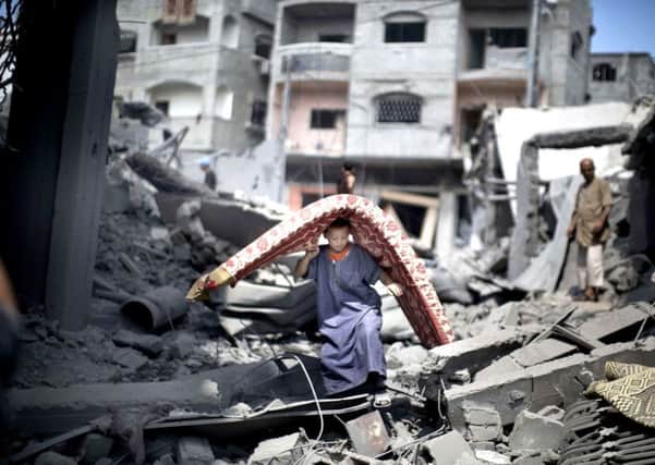 A boy takes a mattress from the ruins after an air strike on a Gaza refugee camp. Photograph: Mahmud Hams/Getty
