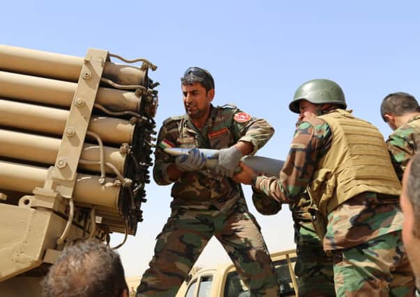 Kurdish peshmerga fighters load missile launcher during the clashes with the army groups led by Islamic State militants. Picture: Getty