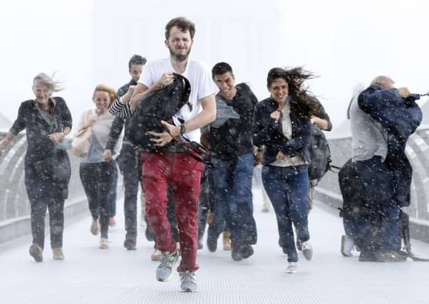 Pedestrians get caught up in high winds and torrential rain on the Millennium Bridge in Southwark, London yesterday as the remnants of Hurricane Bertha swept the south of England. Picture: PA